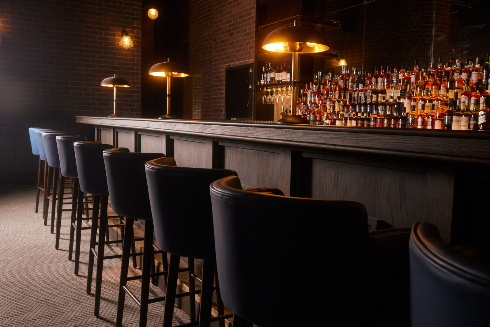 Hickson House long bar with alcohol and lights with high-backed bar chairs